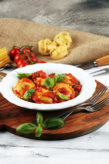 Ravioli with tomato sauce garnished with parmesan cheese and basil on rustic table