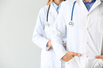 Male and female doctors on light background