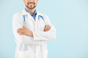Male doctor with stethoscope on light color background