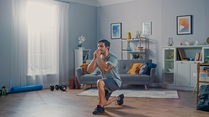 Strong Athletic Fit Man in T-shirt and Shorts is Doing Forward Lunge Exercises at Home in His Spacious and Bright Apartment with Minimalistic Interior.