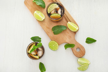 Glasses of cold cola, lime and mint on table