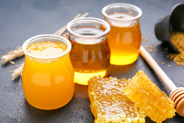 Jars of sweet honey and combs on table