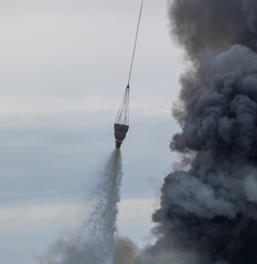 Obraz premium helicopter extinguishes a fire from a basket of water