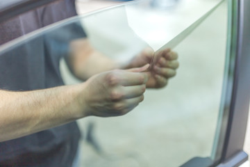 Obraz premium Close up of worker pulling off sun protection tinted foil from side car window.