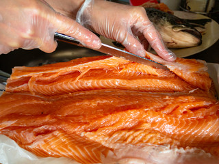 hands cutting a fresh salmon on a cutting board