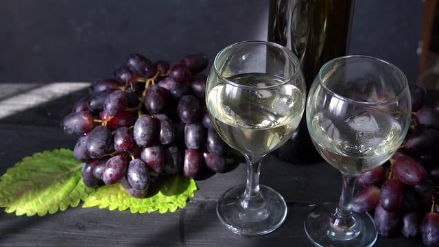 Black grapes, a glass of white wine and a bottle of wine on dark table Video HD