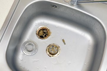 Silvery kitchen sink with a disassembled protective filter during the repair process