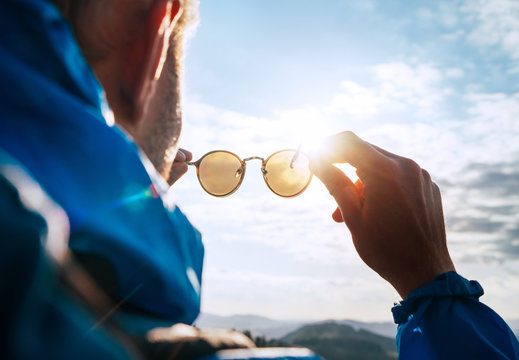 Backpacker man looking at bright sun through polarized sunglasses  enjoying mountain landscape. Eye & Vision Care human health concept image.