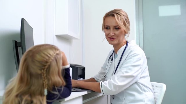 Pediatrician finishes the reception amicably, giving five gesture hand. Young woman doctor pediatrician talking to little girl patient at medical checkup appointment. Shot in slow motion