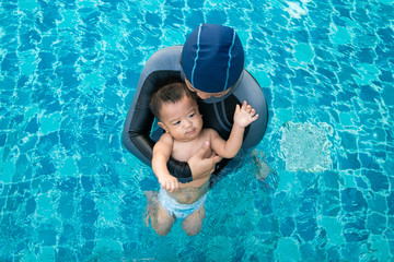 Toddler baby boy enjoying swimming with mom in pool