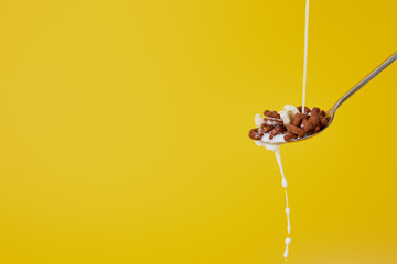 spoon with assorted cereal and milk stream isolated on yellow