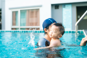 Toddler baby boy enjoying swimming with mom in pool