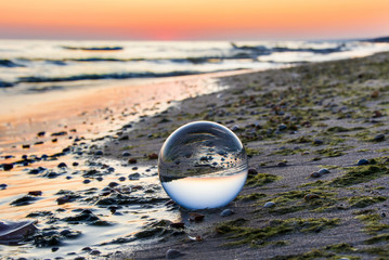 Fototapeta na wymiar Szklana kula na brzegu morza. Piękny wschód słońca
