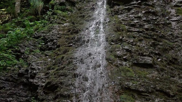 A thick trickle hall and drops of water flow in slow motion from the joints of a layered limestone of the Muschelkalk formation.