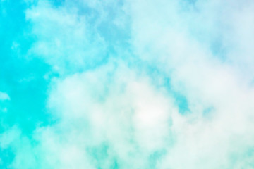 Abstract background of a vibrant teal blue sky with soft puffy clouds