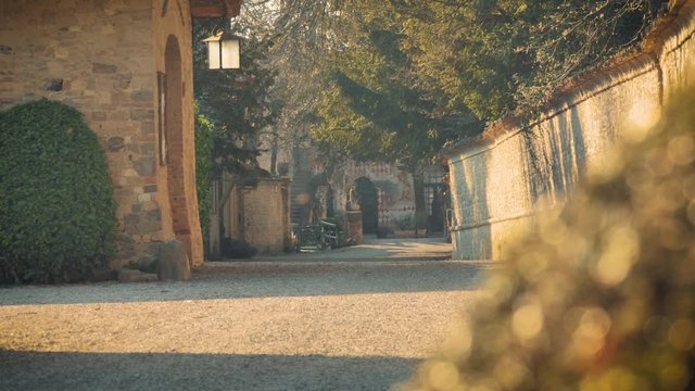 A well maintained gravel road leads the way to other stone and tile buildings inside the fortress of Grazzano Visconti, Italy.