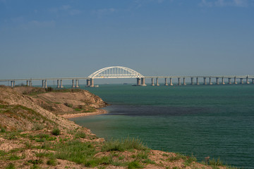 Crimean bridge next to the sandy beach on the sea