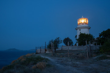 White sea lighthouse in Feodosia, Crimea on the Black Sea from the light under the evening sky