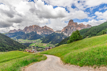 Fototapeta na wymiar Picturesque alpine road leading to the city Corvara in Badia and Italian Dolomites with a peak Sassongher in the background.