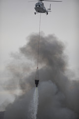 Obraz premium helicopter extinguishes a fire from a basket of water
