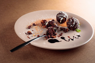 Chocolate balls with mint on a beige plate.
