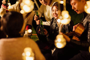 Group smiling friends with acoustic guitar singing and drinking beer