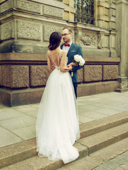 Bride and groom hugging against the wedding palace. They are completely in love.