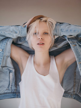 Young human in jean jacket and hat with hands on head