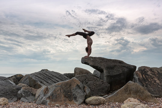 A young man performing a balancing act on the seashore.