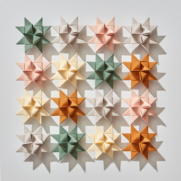 Composition from multi-colored paper stars origami on a gray background with reflection of shadows. Pattern as a layout for postcards. Flat lay