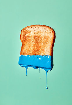 A piece of fried toast painted blue presented on a green background with splashes and copy space.