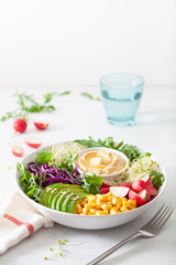 vegan avocado sweet corn lunch bowl with hummus, red cabbage, radish and sprouts
