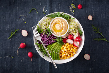 vegan avocado sweet corn lunch bowl with hummus, red cabbage, radish and sprouts