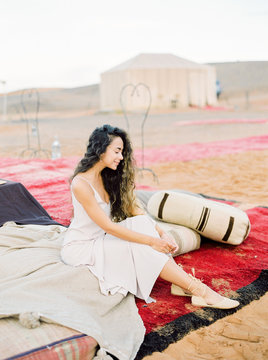 A portrait of a dark-haired woman in a desert camp wearing morrocan dress