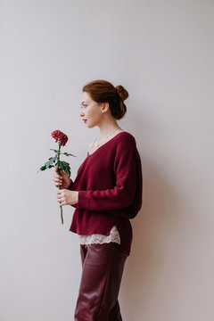 Side view portrait of stylish woman with red flower by the white background