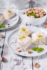 Cotton candy with pistachio on ceramic plate on white wooden table