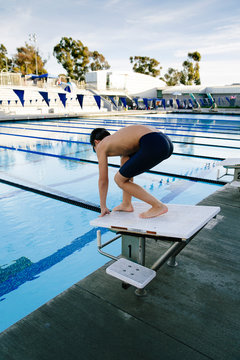 Boy in ready form to jump into pool on diving board