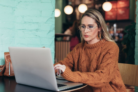Woman with autumn outfit working inside coffee bar.