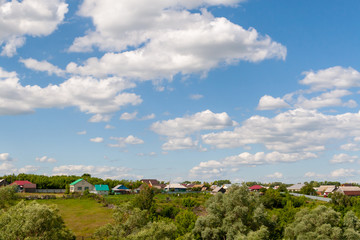 Summer afternoon over a Russian village. Beautiful white clouds in the blue sky over the Russian village.