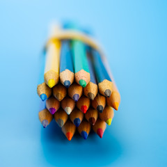 bunch of colored pencils lies on a blue background.