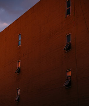 ed brick facade with small windows at sunset