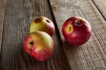 apples with small rotten spot on brown wooden surface