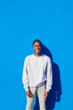 Young laughing black man on blue wall