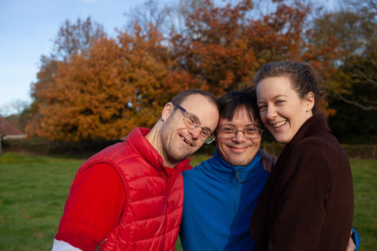 Three adoptive siblings hug and smile.