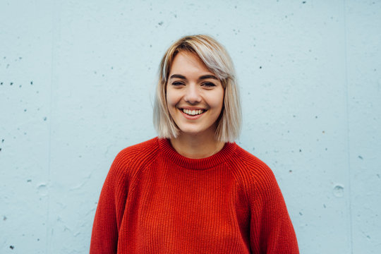 Beautiful Blonde Woman In Red Sweater Against The Blue Background