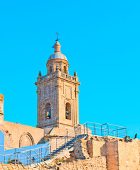 Bell along with ruins of a church that has no roof,