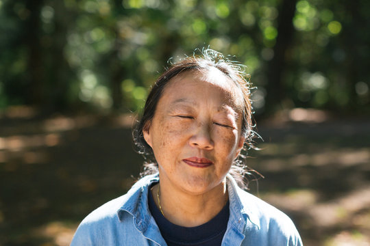 Mature Asian Woman Practicing Tai Chi Outside.