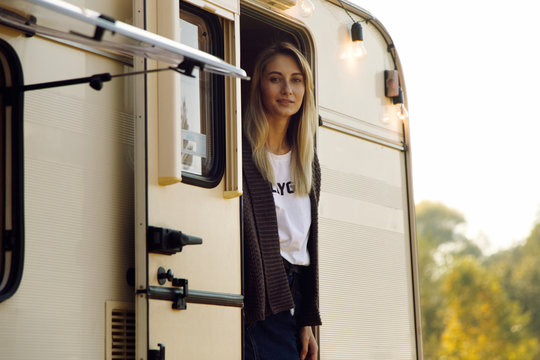 Young woman standing in doorway of caravan