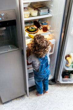 Unrecognizable child taking a banana from fridge at home