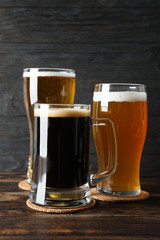 Different mugs with beer on wooden table, copy space